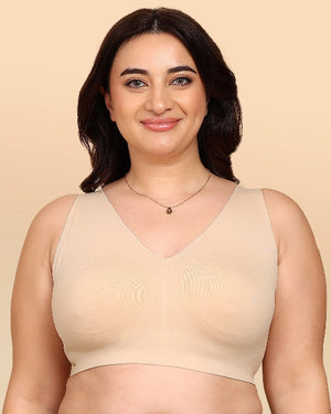 Woman wearing a beige tank top against a beige background