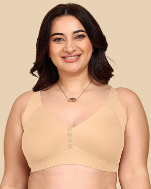 Woman wearing a beige bralette with decorative buttons on a beige background