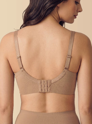 Woman wearing a beige bra against a beige background