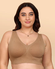 Woman wearing a beige bralette against a beige background