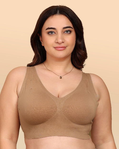 Woman wearing a beige bralette against a beige background