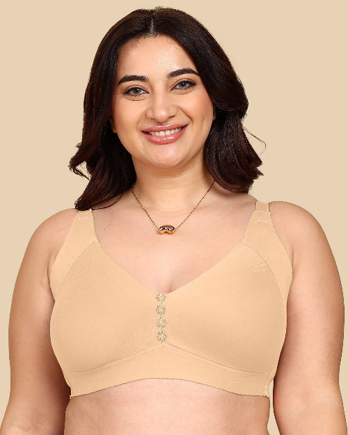 Woman wearing a beige bralette with decorative buttons on a beige background