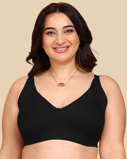 Woman wearing a black bralette against a beige background