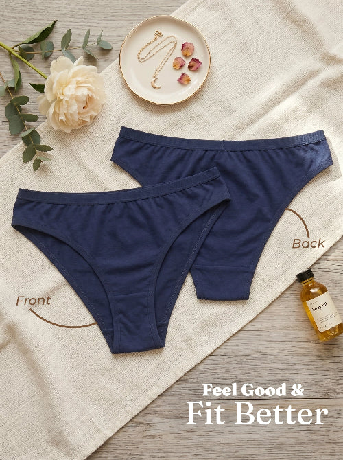Navy blue underwear on a textured surface with decorative elements like a flower and jewelry.