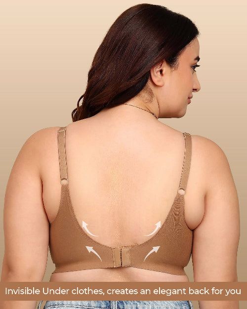 Woman wearing a beige bralette with a plain background