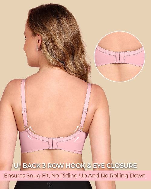 Woman wearing a pink bra with a close-up of the back closure on a beige background.