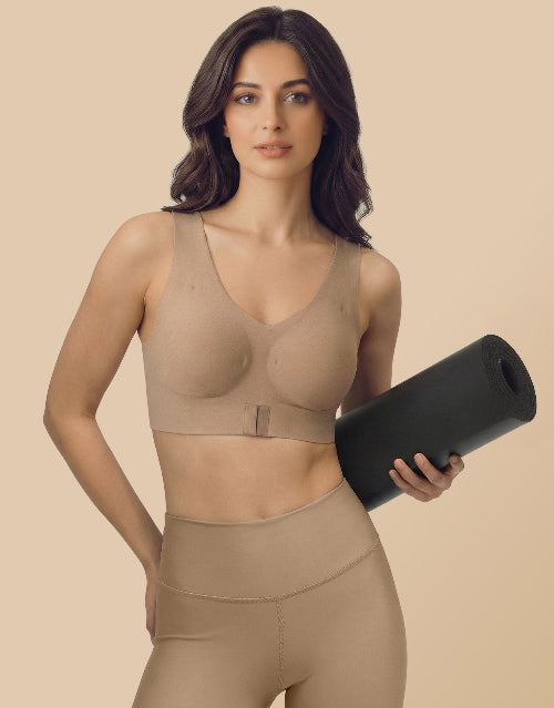 Woman wearing a beige compression garment holding a black mat on a beige background